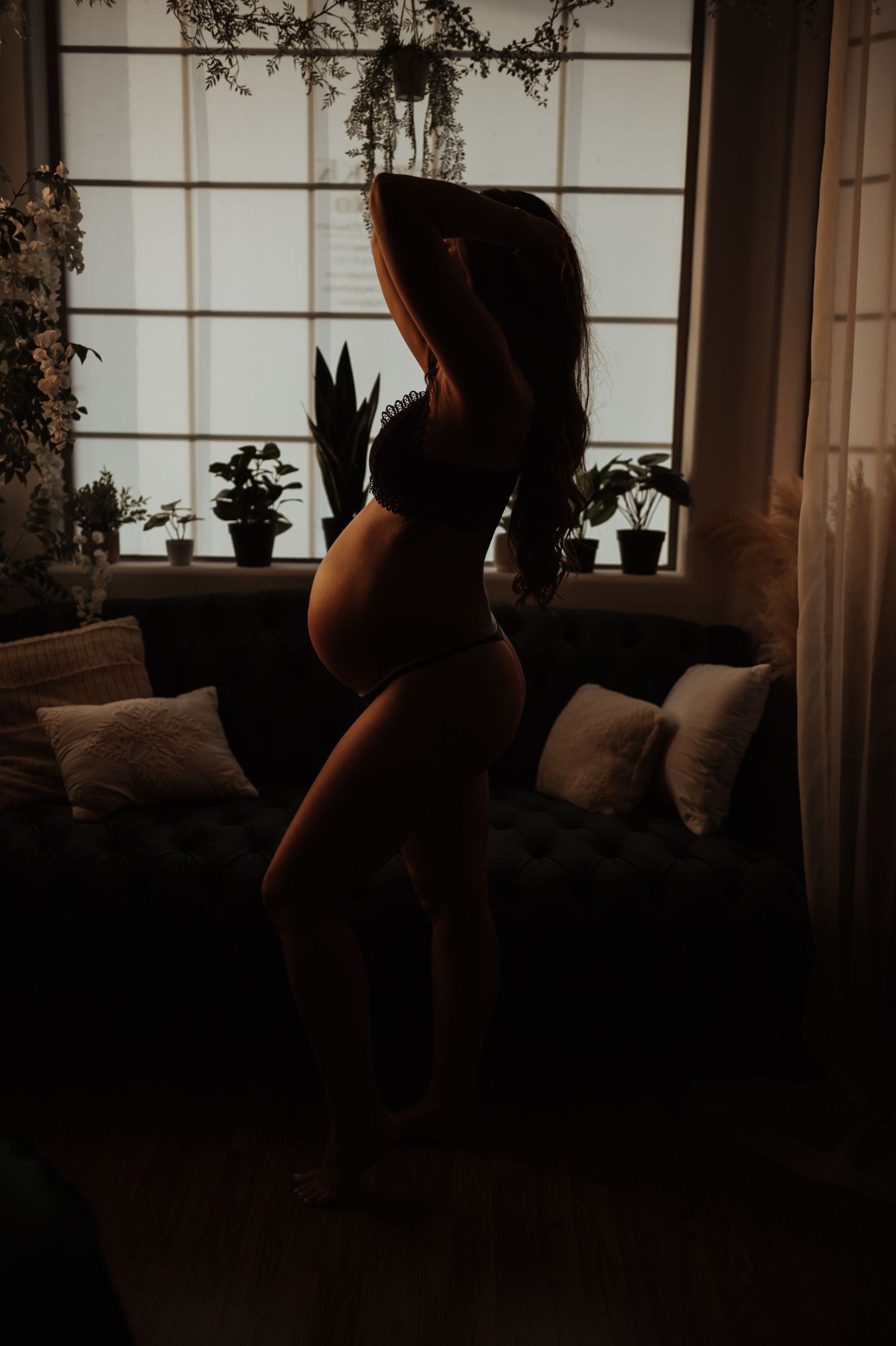 Moody silhouette portrait by window with houseplants.