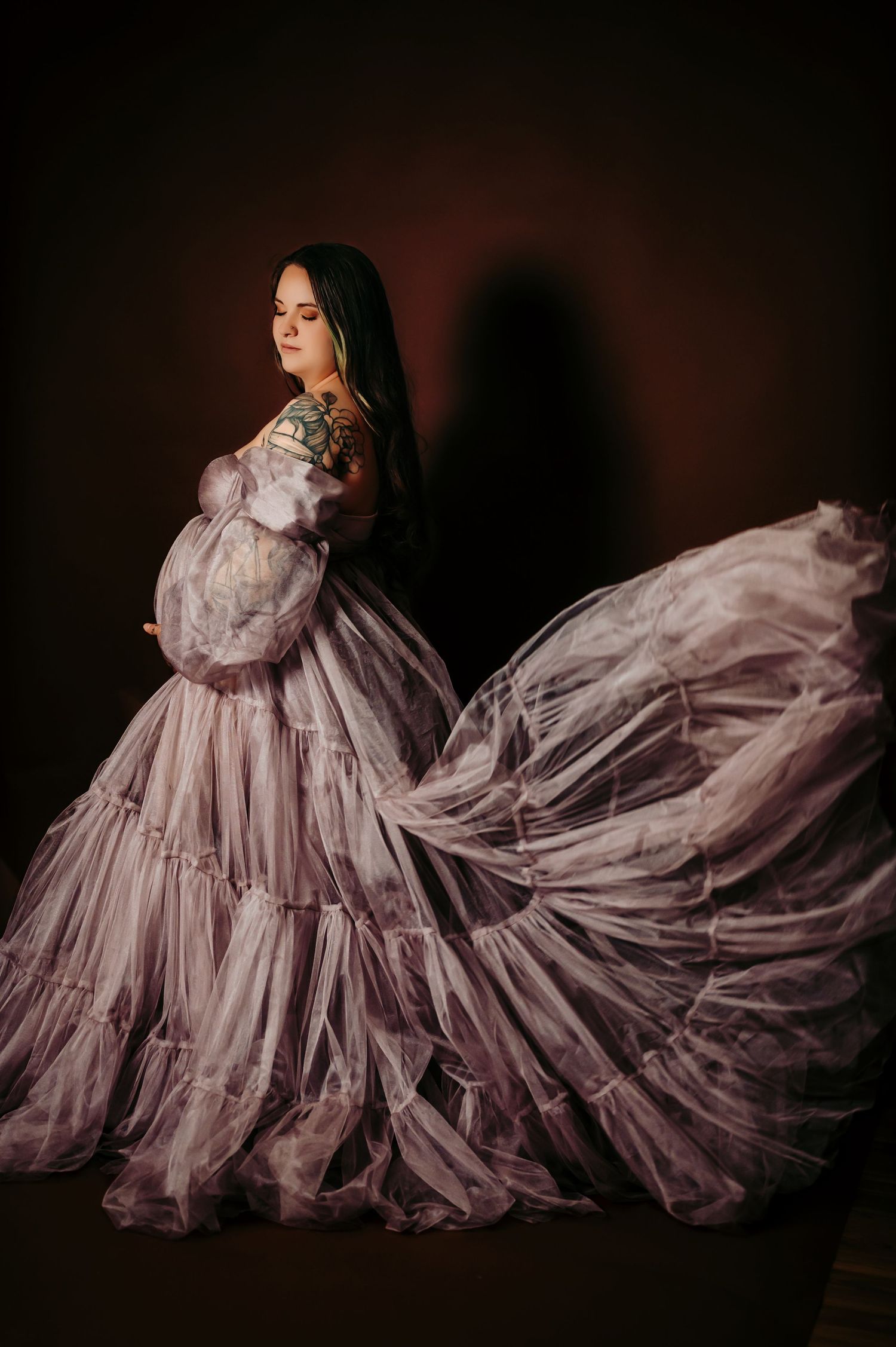 Flowing lavender dress creates dramatic movement in dark studio portrait.