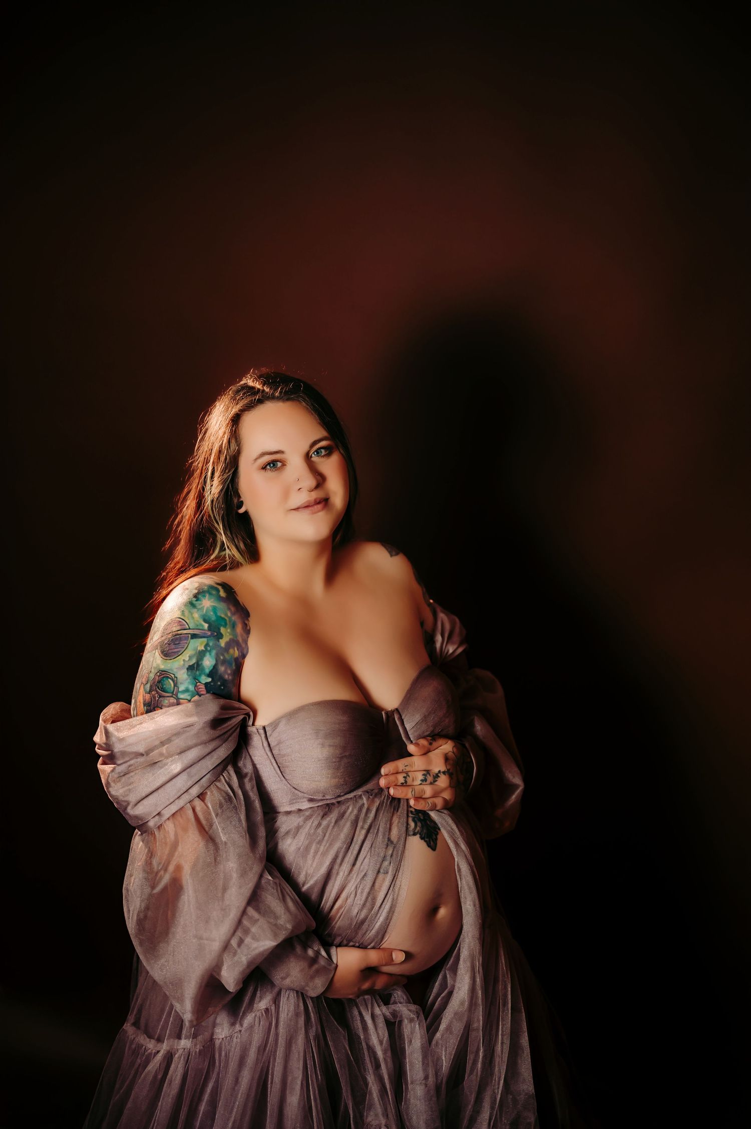 Elegant portrait in flowing purple gown against dark background.