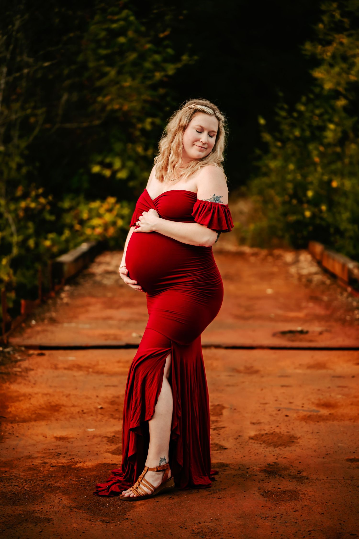 A flowing red velvet dress photographed in a series of poses against a rustic outdoor setting with reddish soil.