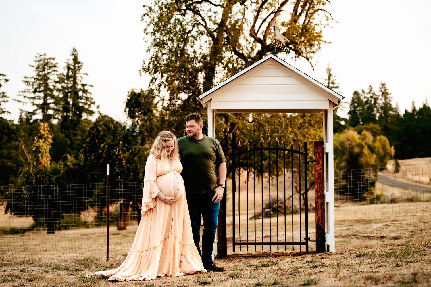 Romantic photoshoot at sunset near a white gazebo with soft peachy tones and natural lighting.