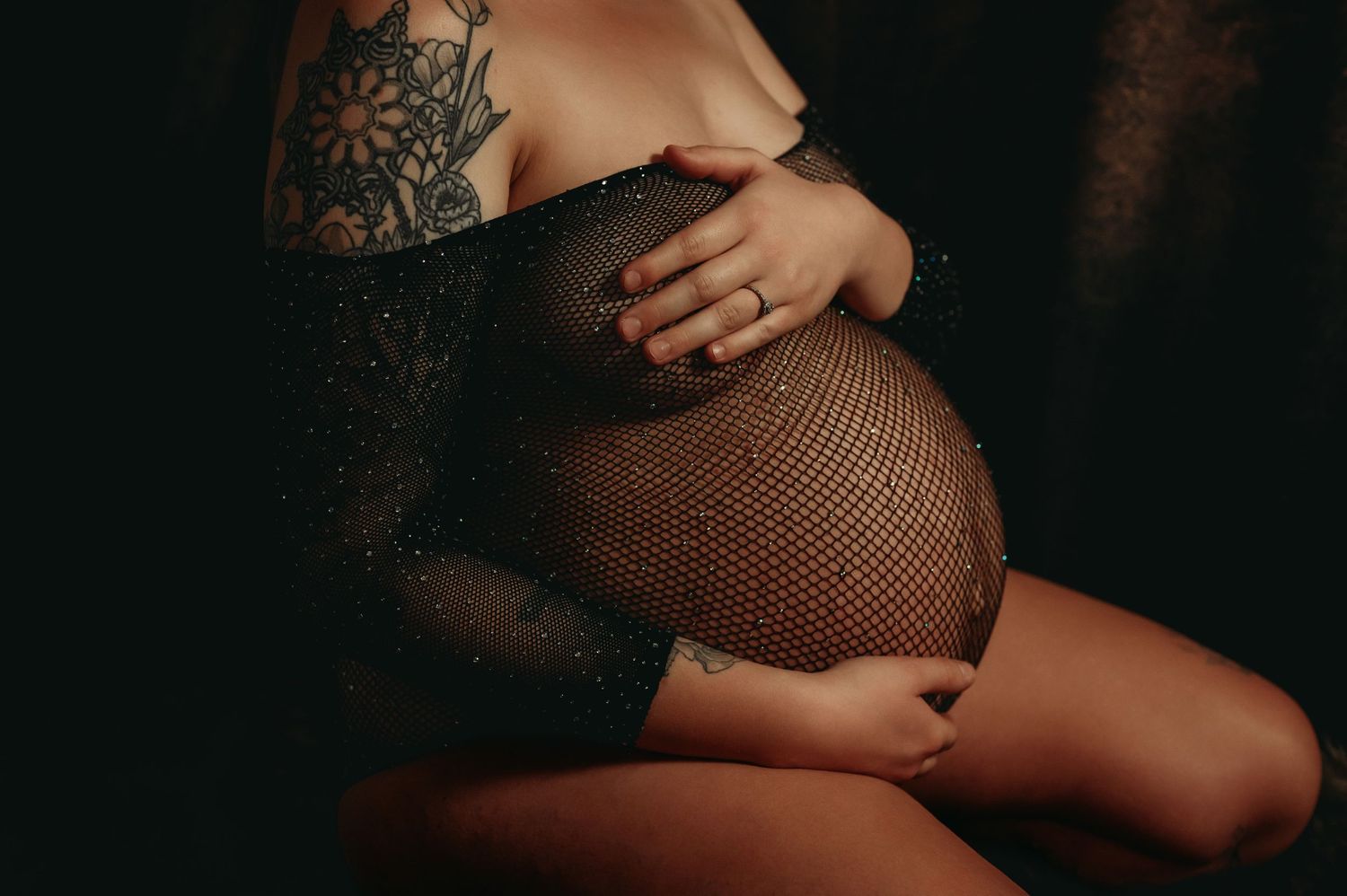 Intimate maternity portrait featuring mesh fabric and visible tattoo artwork.
