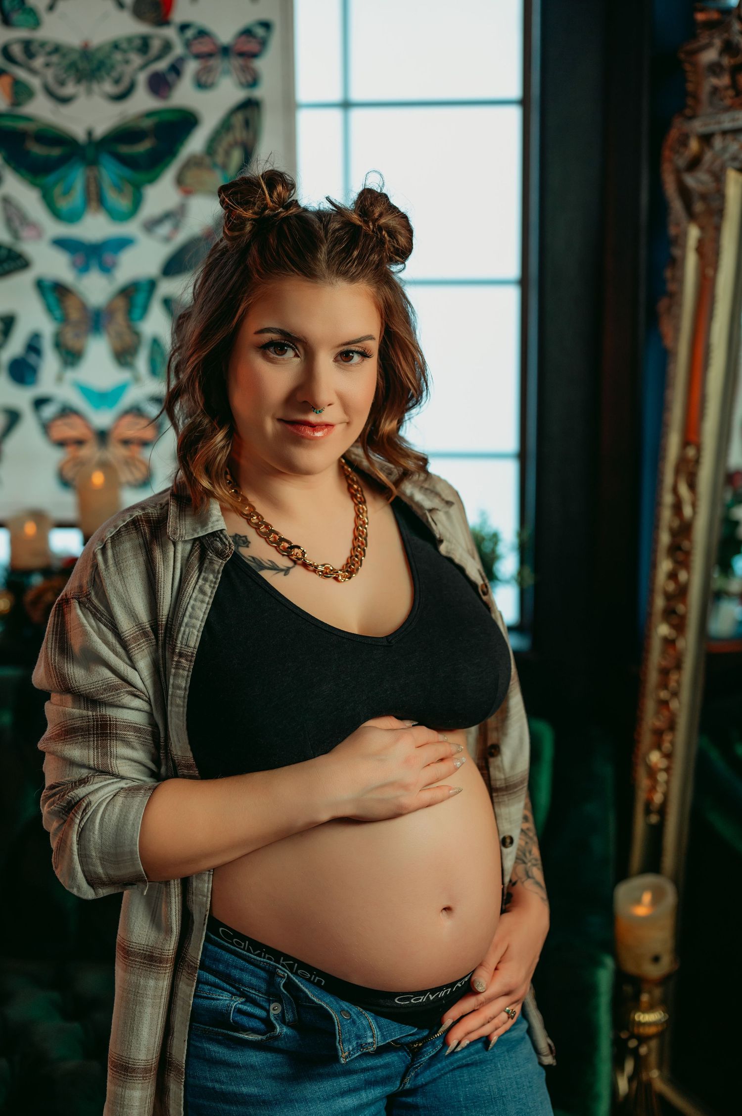 Casual maternity portrait with butterfly wall decor and natural window light.