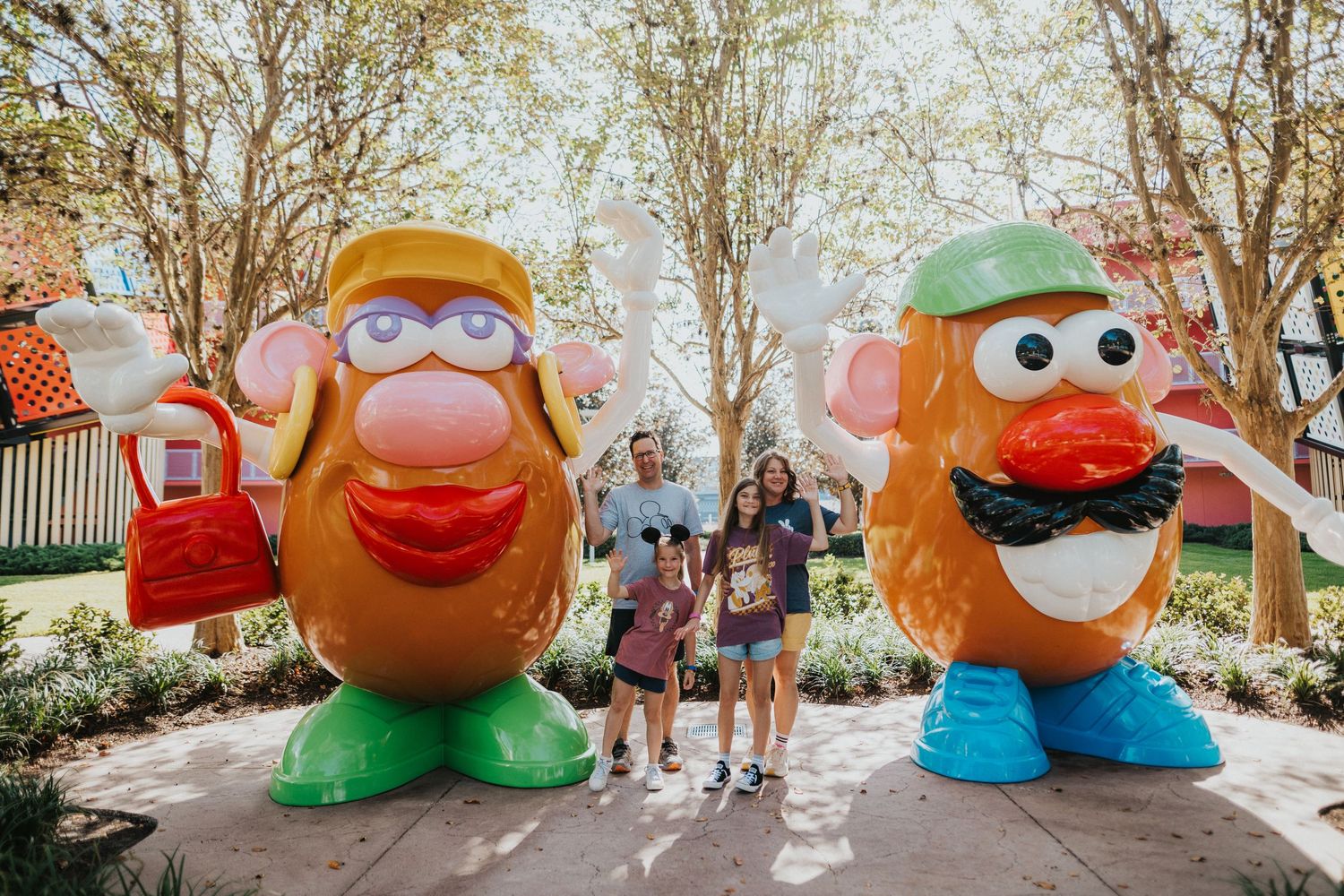 A family posing with giant Mr. and Mrs. Potato Heads at Pop Century Resort in Disney World.