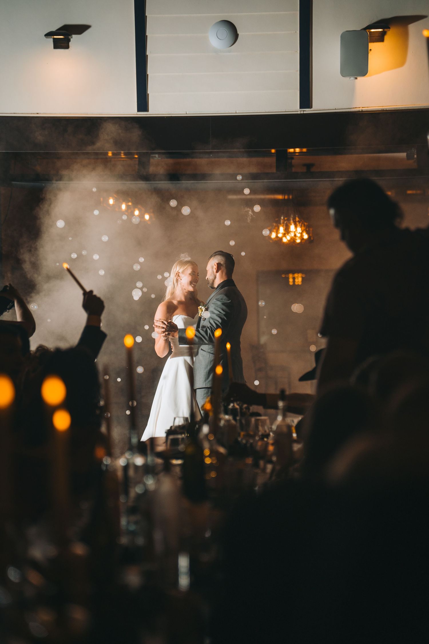 Outdoor wedding ceremony setup with wooden barrels and rustic arch against sunset sky.