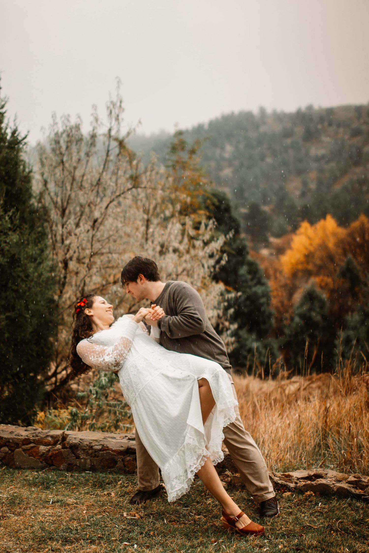 Couple celebrating with champagne spray in autumn forest with golden foliage.