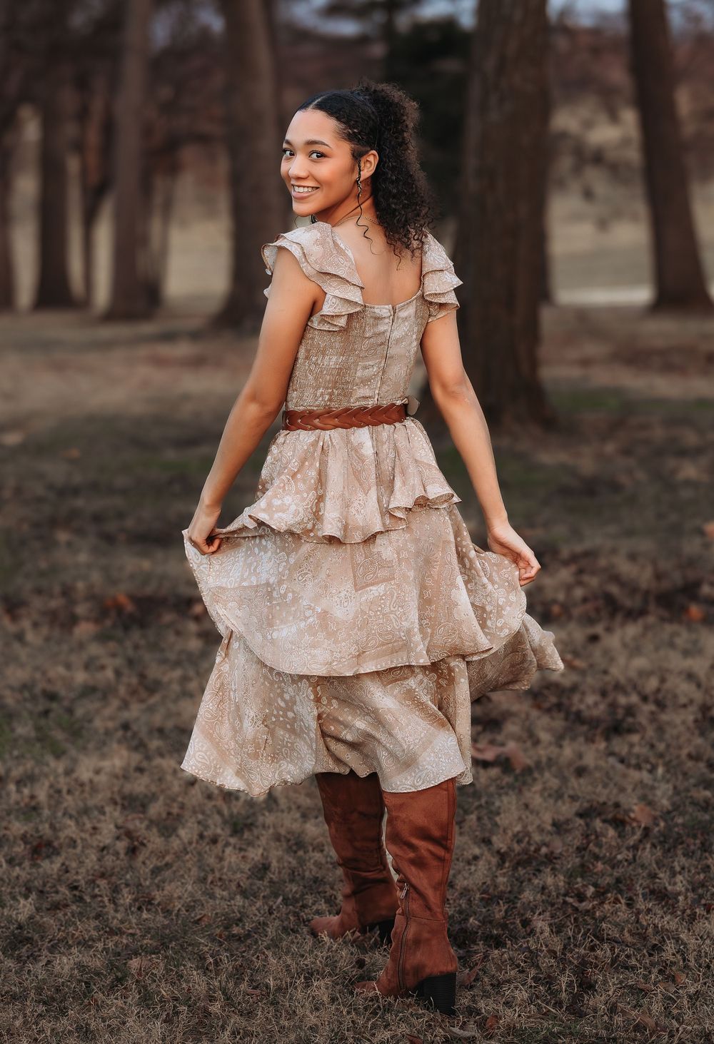 A flowing beige ruffle dress paired with tall brown boots creates a romantic outdoor portrait.