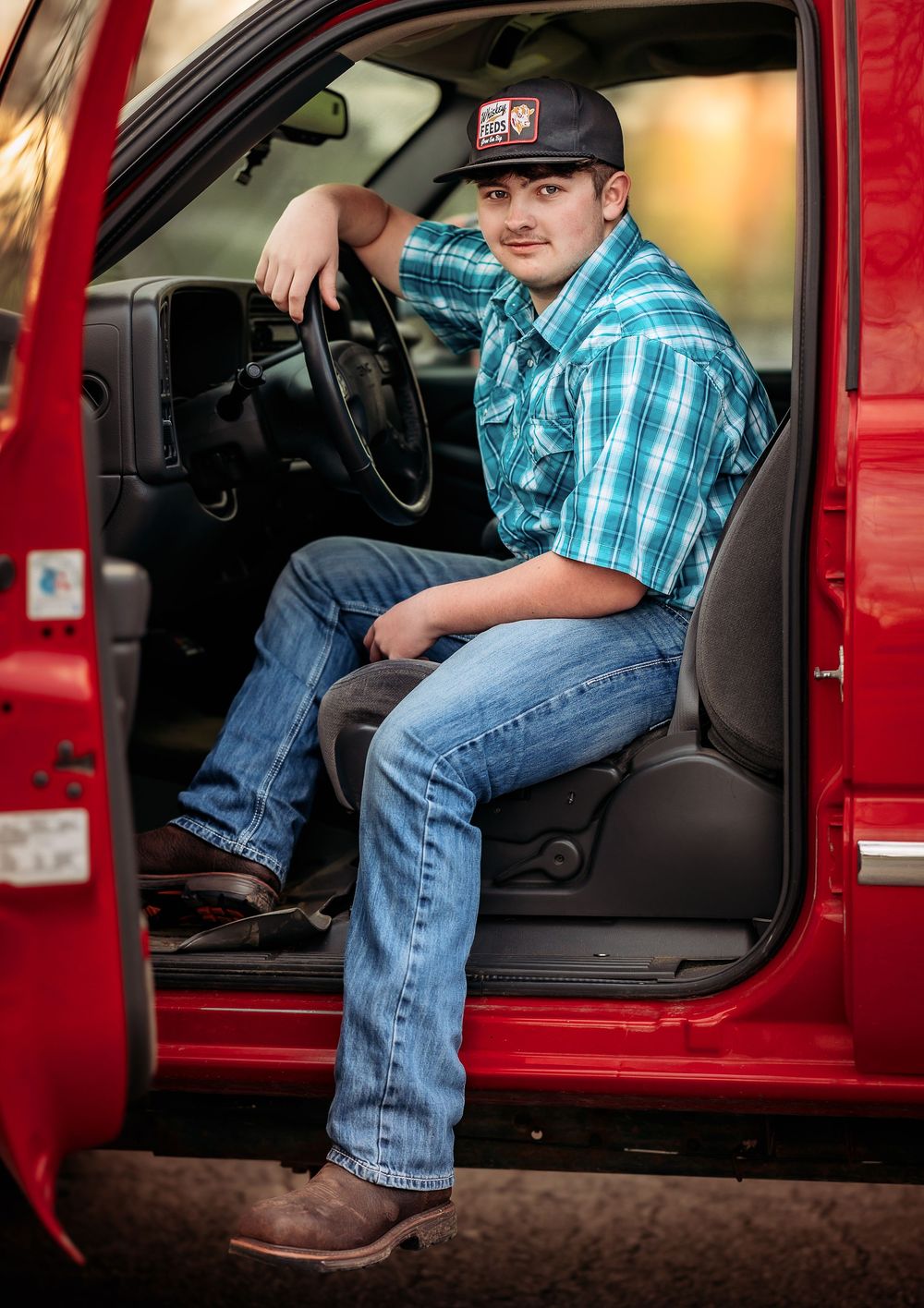Person in plaid shirt and jeans poses with red pickup truck door showing progression of stepping into vehicle.