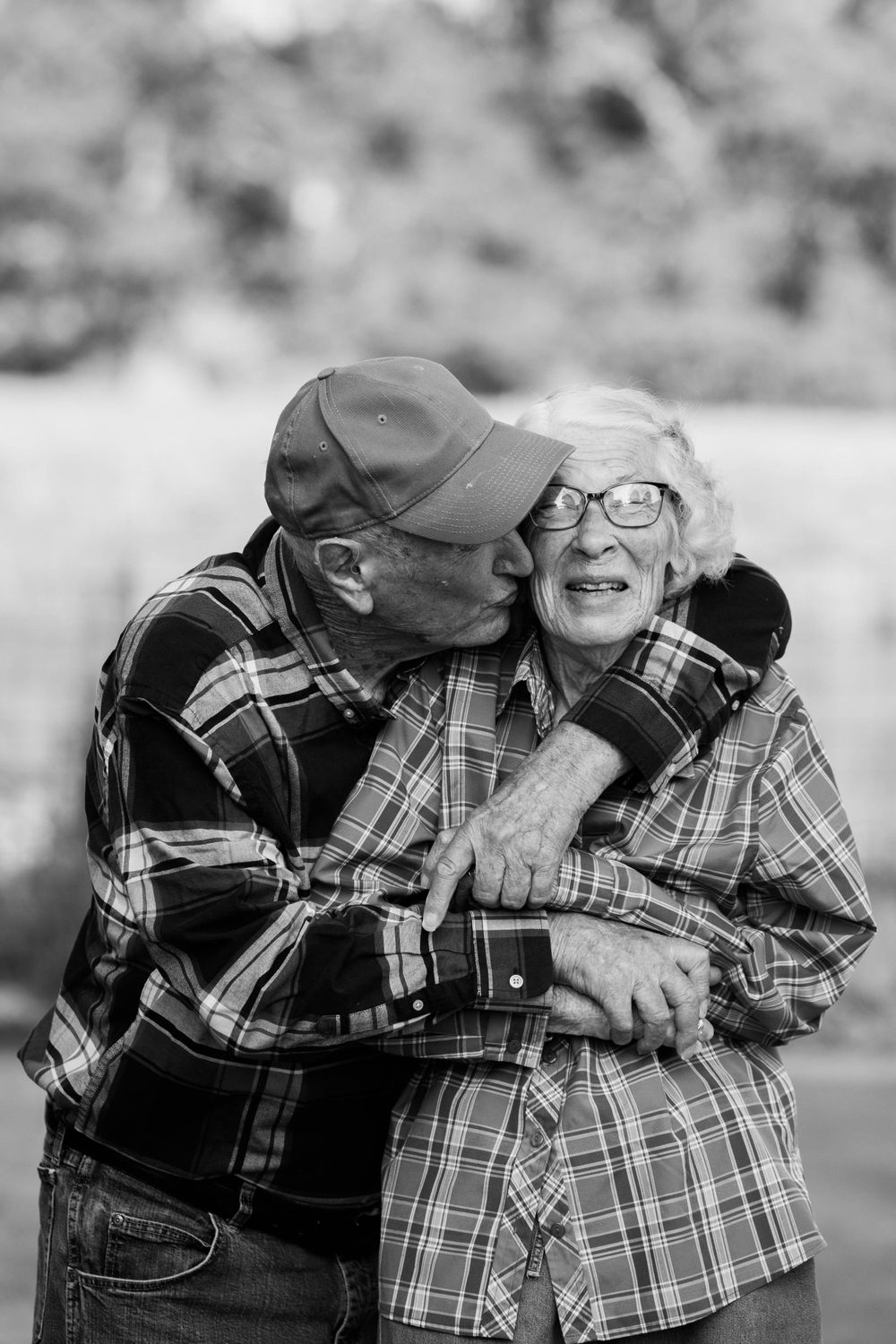 An intimate black and white photo sequence showing a sweet embrace with laughter in plaid clothing.
