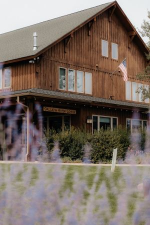 A rustic wooden lodge with white trim and purple lavender flowers in the foreground.