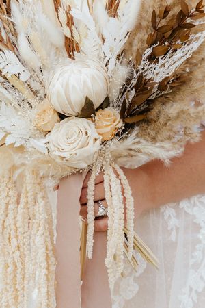 Elegant dried floral arrangement with white roses and pampas grass in neutral tones.