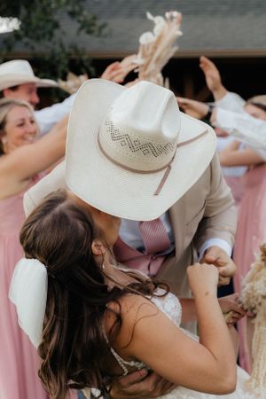 A celebratory moment at a Western-themed wedding with a white cowboy hat.