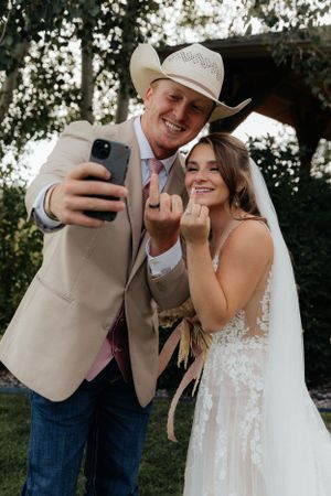 A joyful wedding moment captured while taking a selfie in country western attire.