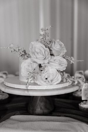 Elegant white roses arranged on a cake stand in black and white photography.