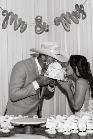 A playful cake-cutting moment at a western-themed wedding reception.