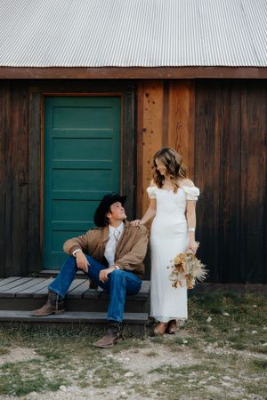 A rustic barn photoshoot with a white dress and casual attire against a teal door.