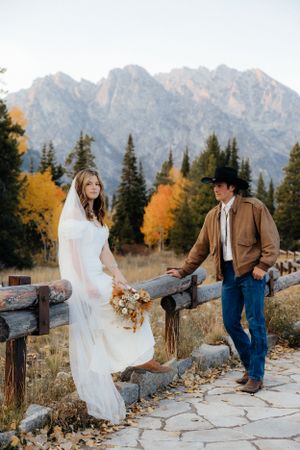 Rustic western wedding photo with mountains and fall foliage in background.