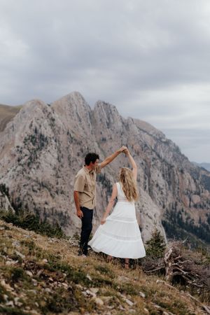 A couple dancing on a mountain ridge with dramatic peaks in the background.