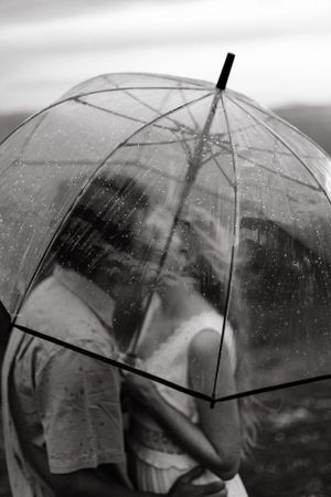 A transparent umbrella with raindrops against a moody black and white background.