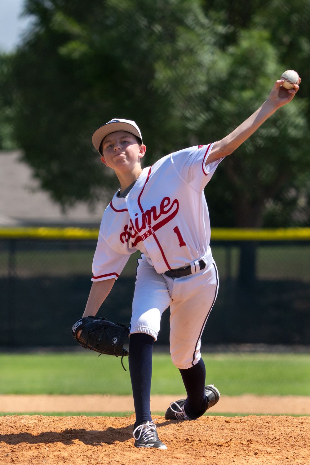 Pitcher in College Station, Texas, delivering a pitch on the field, showcasing athletic skill and focus.