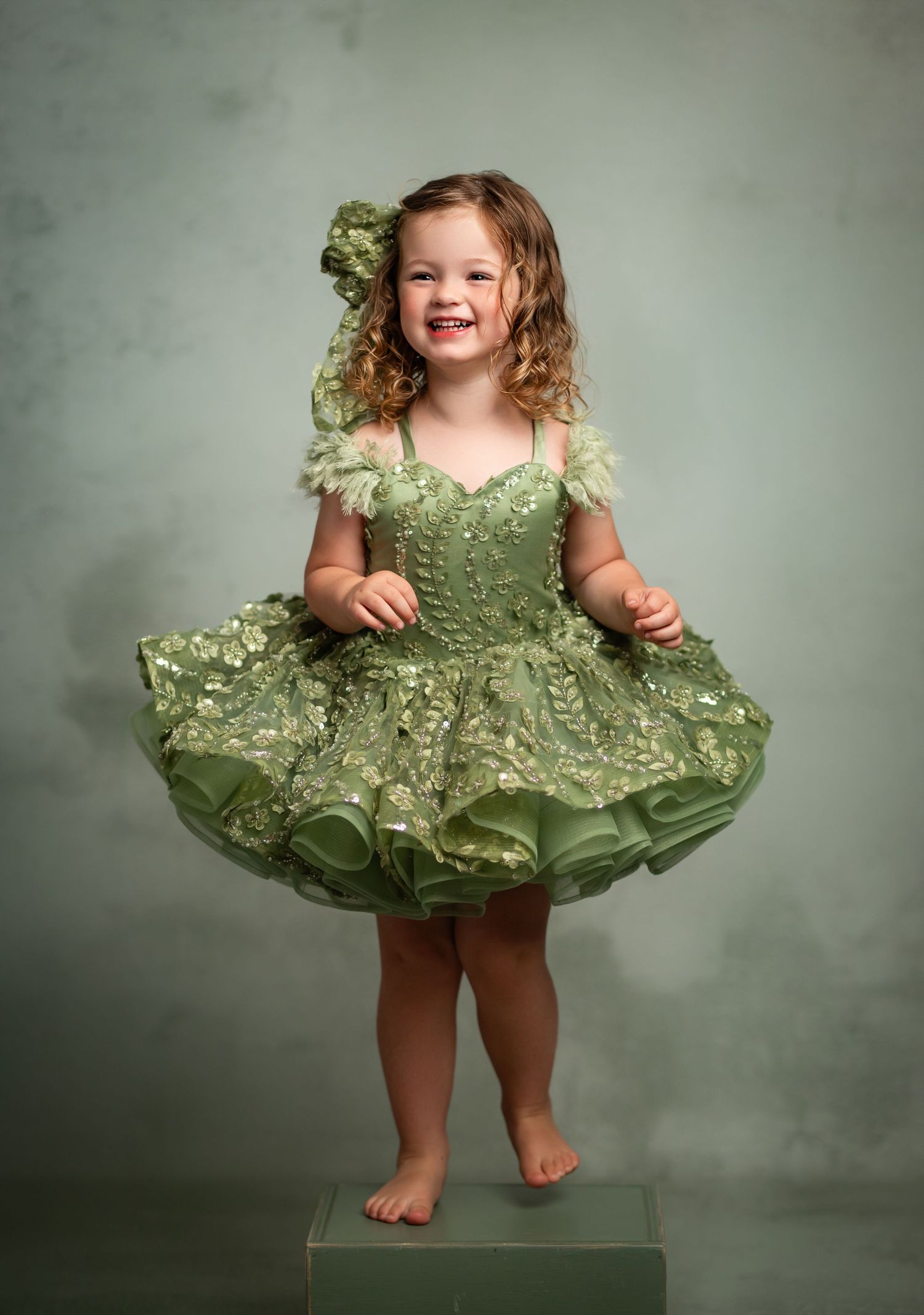 Green vintage-style dress on wooden bench against bokeh background.