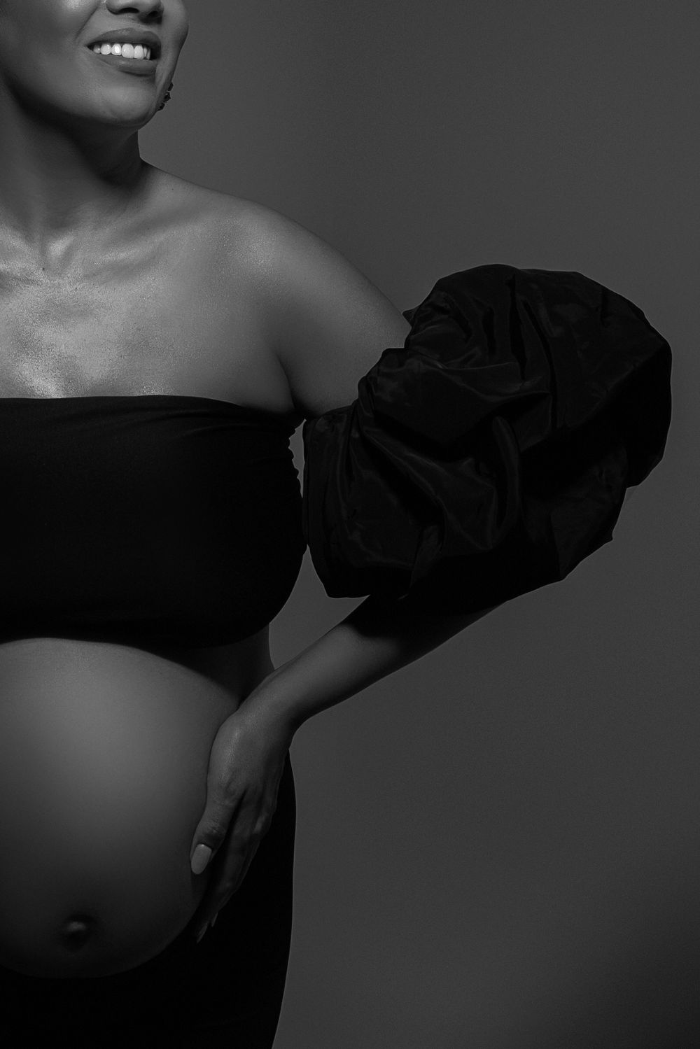 Artistic black and white close-up maternity portrait featuring strapless dress with ruffled detail.
