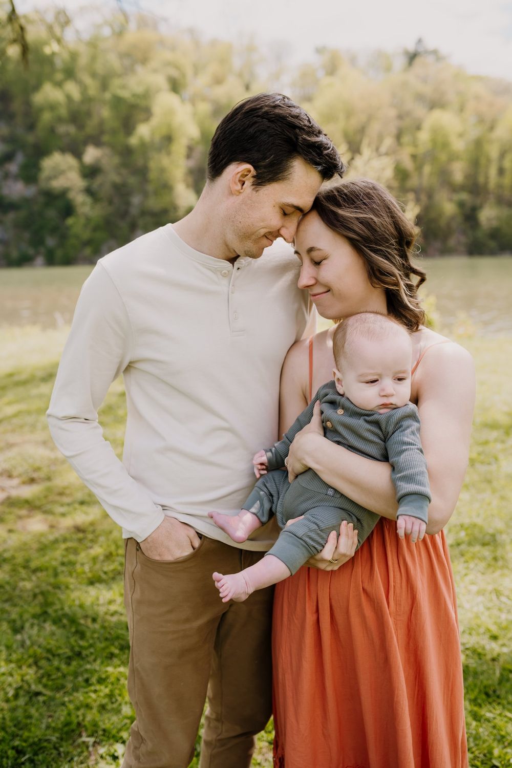 Mom and dad rest foreheads while holding baby