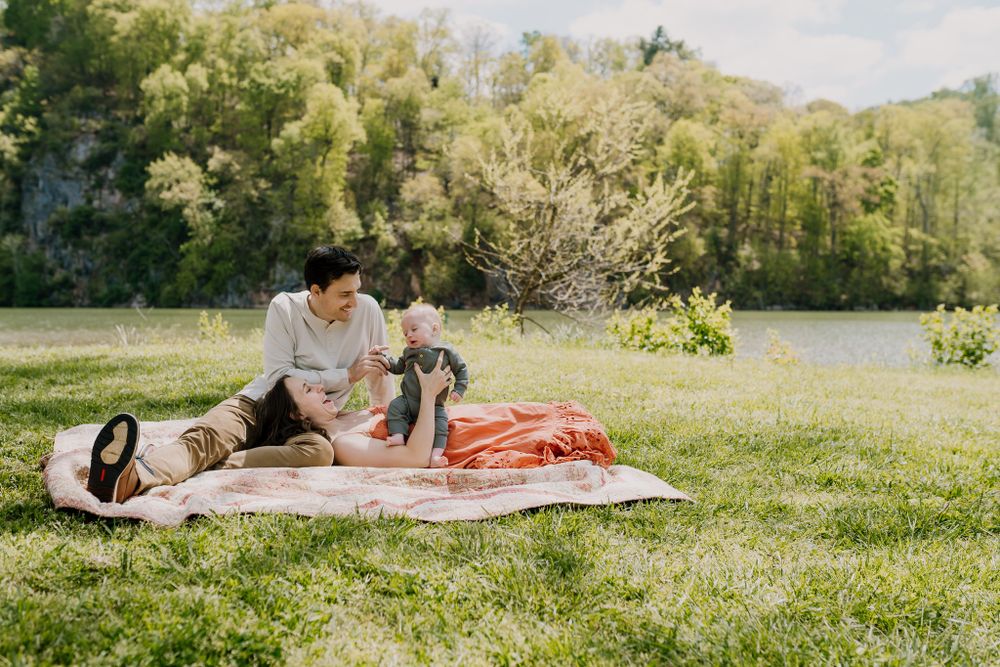 Family sits on a blanket and plays together