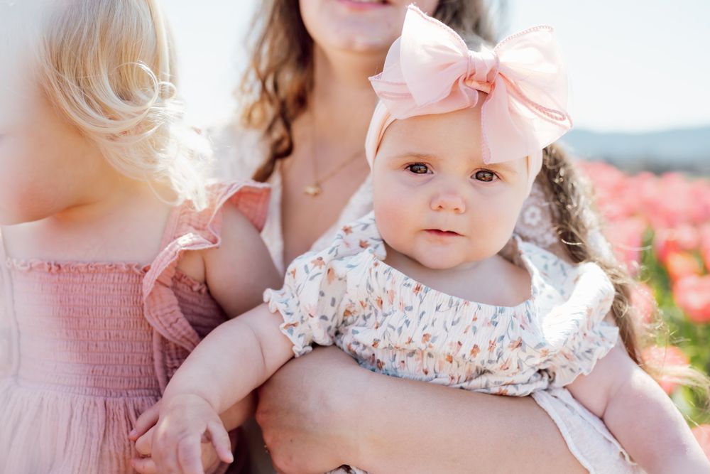 little girl looks at camera from her mom's arms