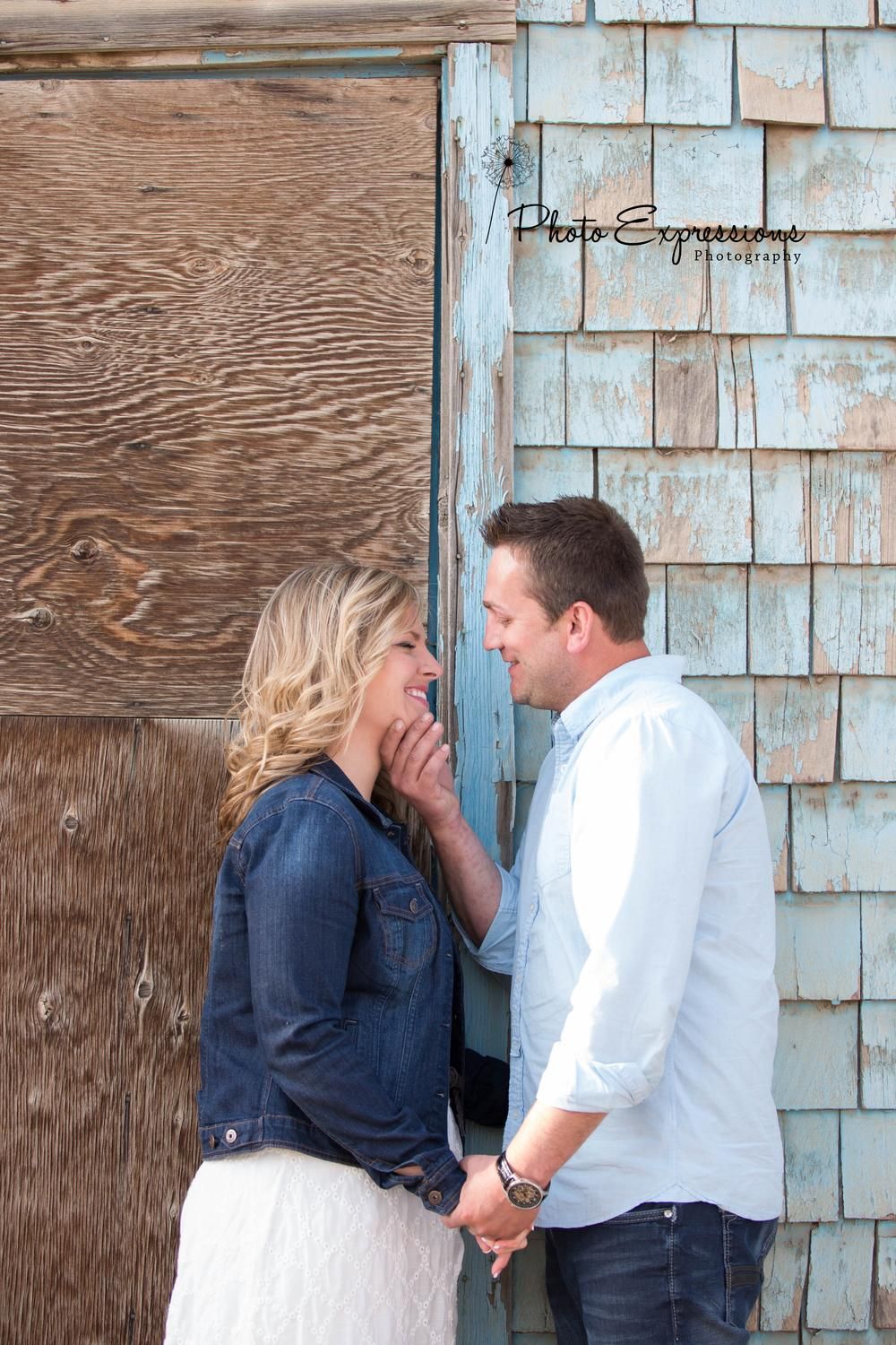 Couple sharing intimate moments against a rustic blue wooden wall background.