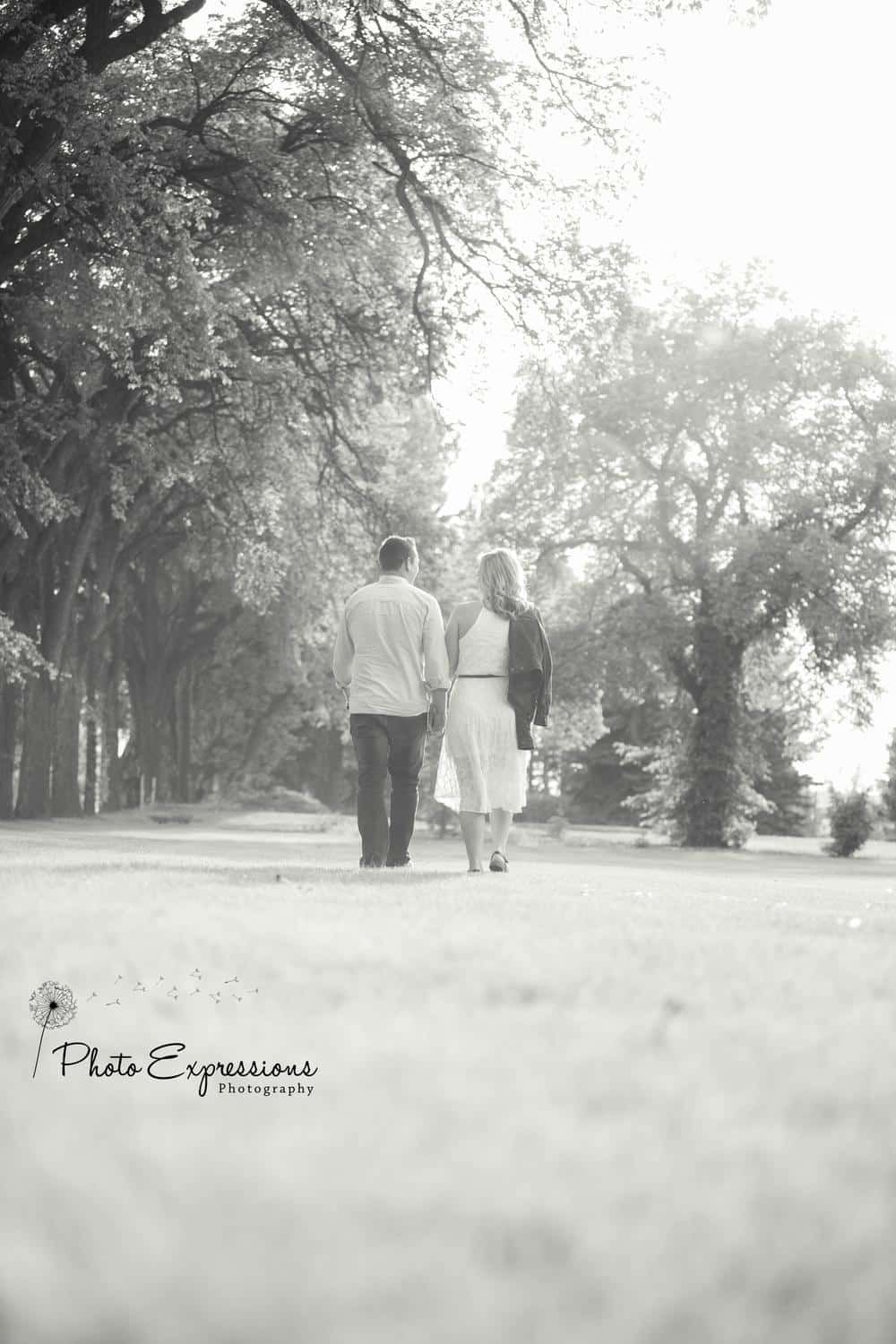 Silhouetted couple walking together through a misty park landscape.