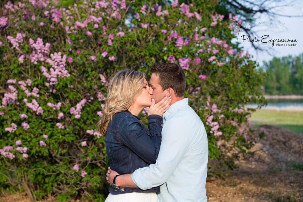 A romantic couple's portrait session among blooming pink flowers outdoors.
