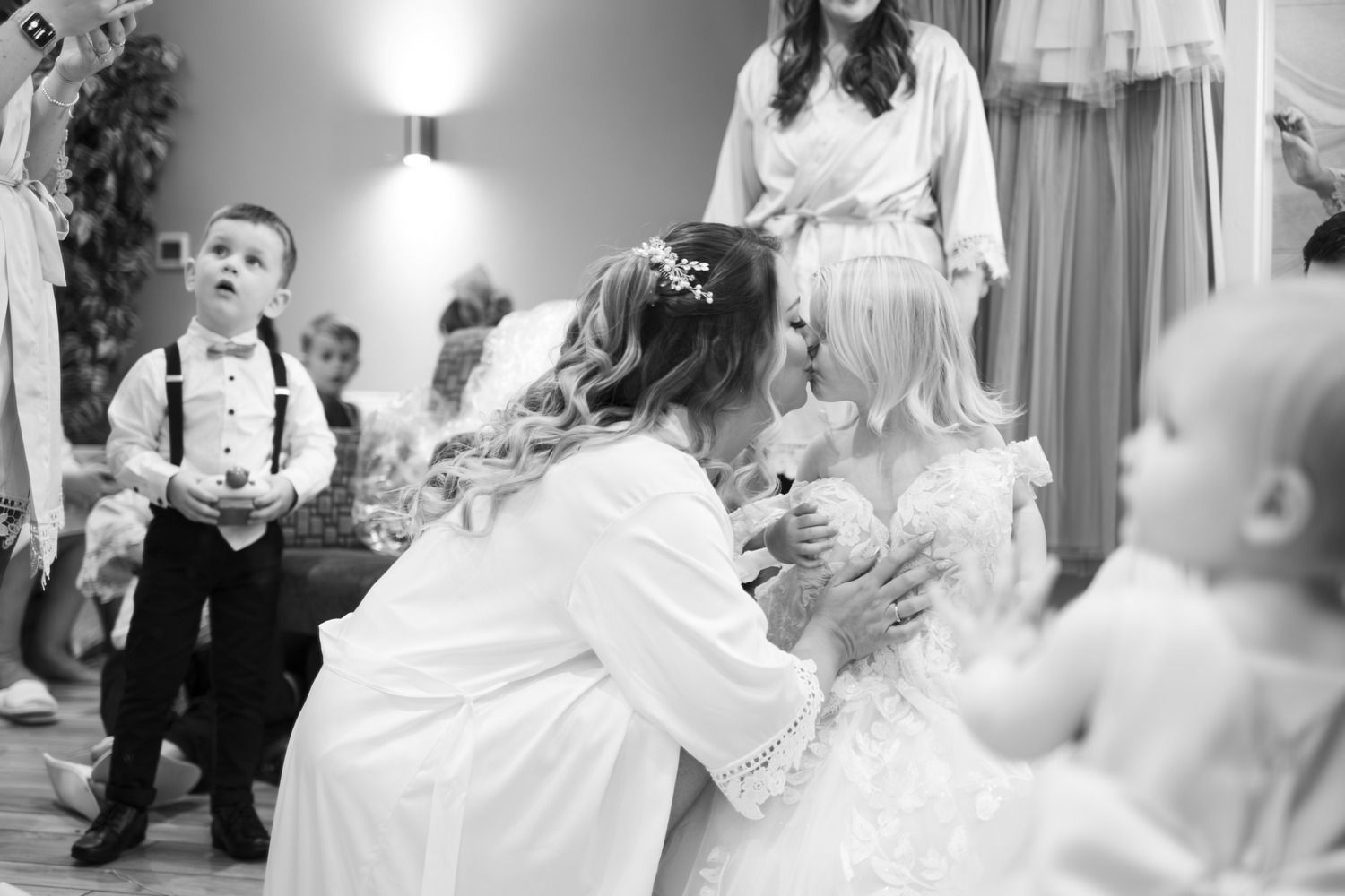 The bride sharing a tender moment with a young flower girl as they get ready, both dressed in beautiful white lace.