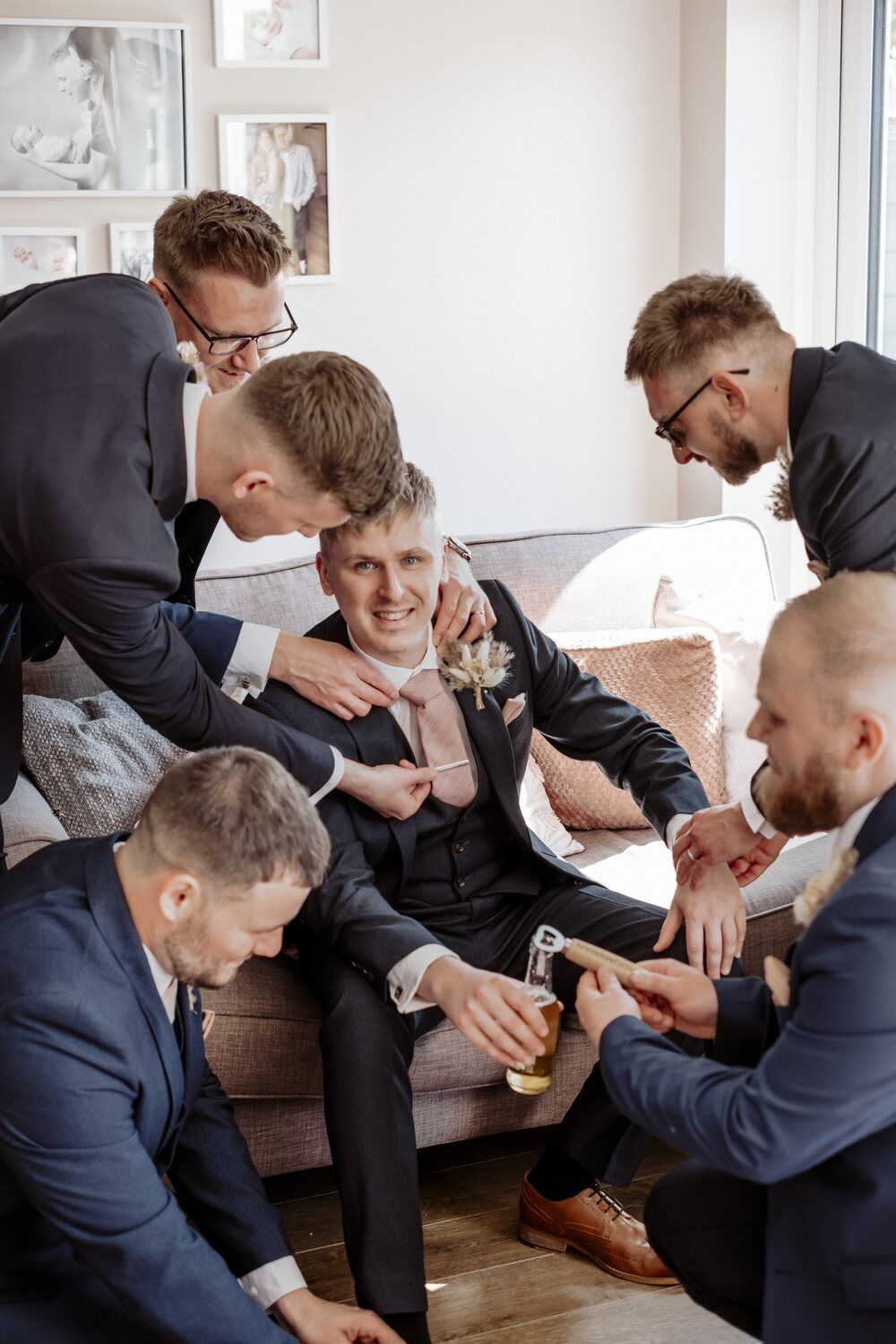 The groom surrounded by his groomsmen, all helping him prepare for the big day with laughter and camaraderie.