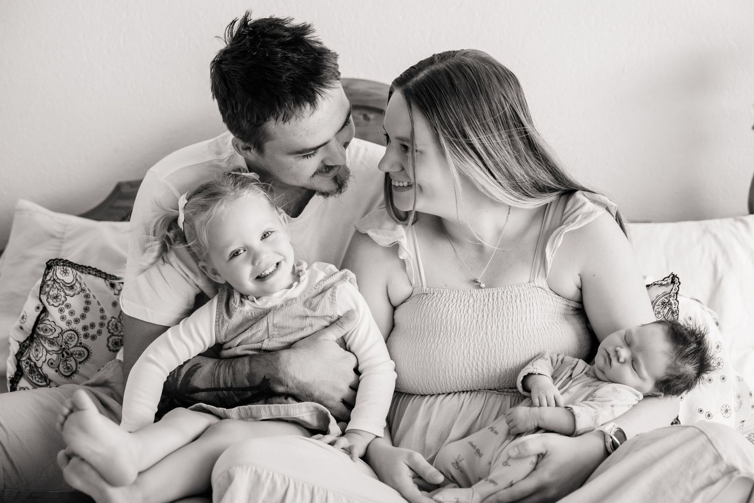 A family relaxes together on a couch at home with their young children.
