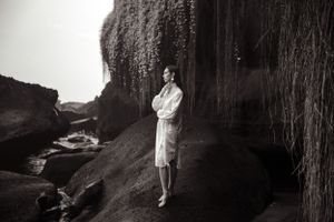 Black and white photo of figure standing beneath dramatic weeping willow tree.
