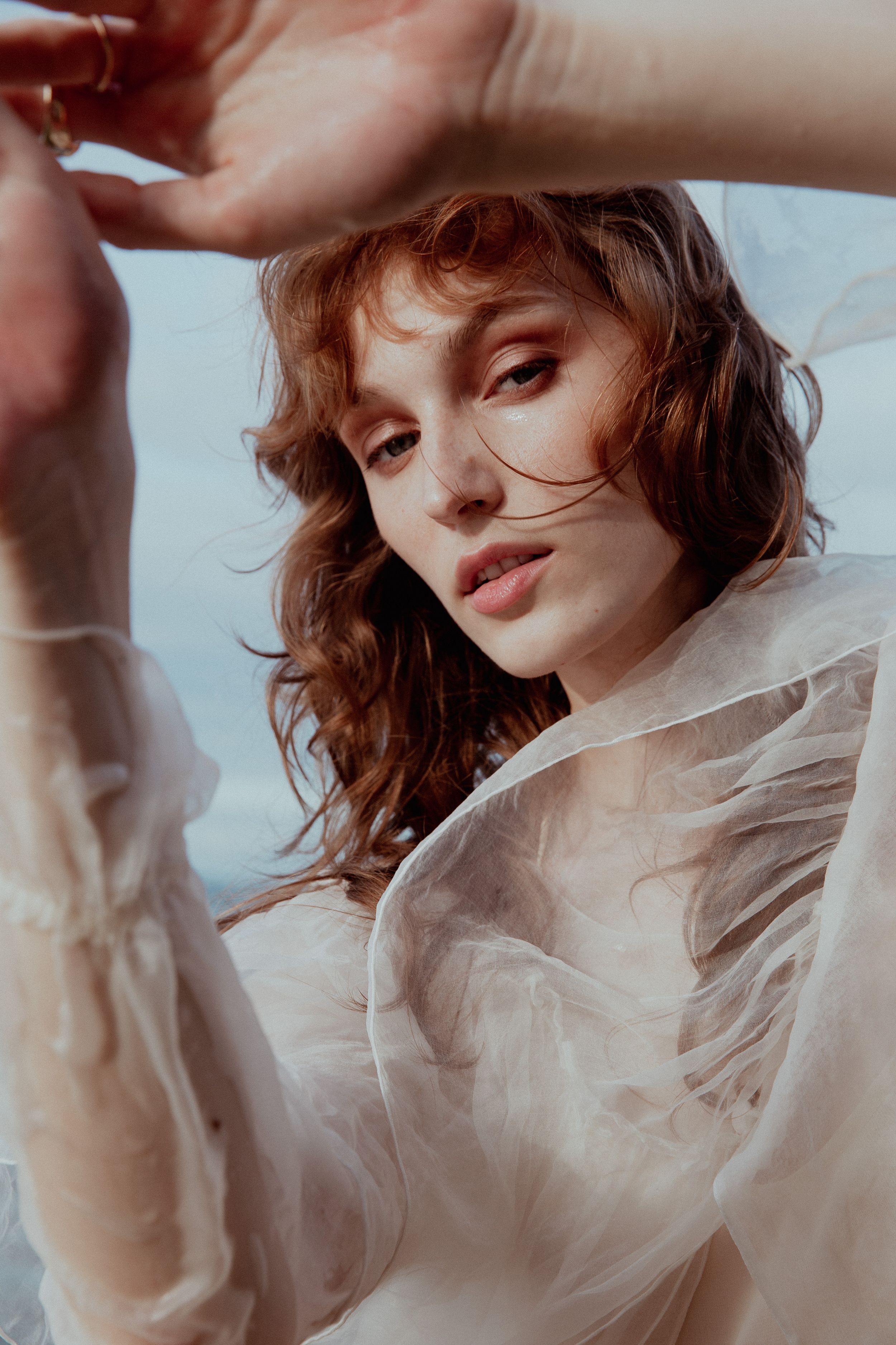 Dreamy close-up portrait with delicate sheer fabric and soft lighting.