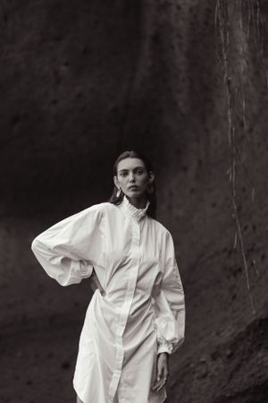 Dramatic black and white fashion photo against textured rock wall background.