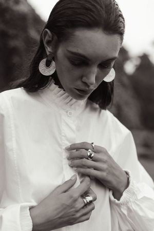 Fashion detail shot showcasing statement jewelry and white ruffled collar blouse.
