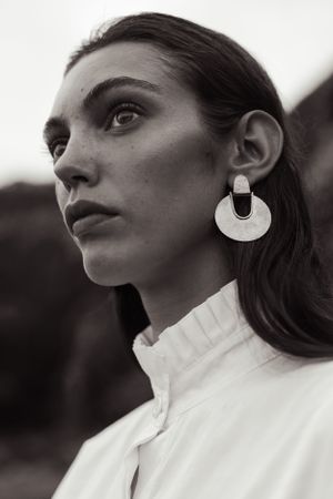 Side profile fashion portrait with dramatic circular earring and high-necked white blouse.