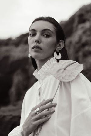 Fashion portrait in black and white featuring white ruffled collar blouse and statement earrings.