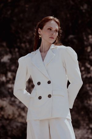 Classic white power suit with structured shoulders photographed in dramatic lighting.