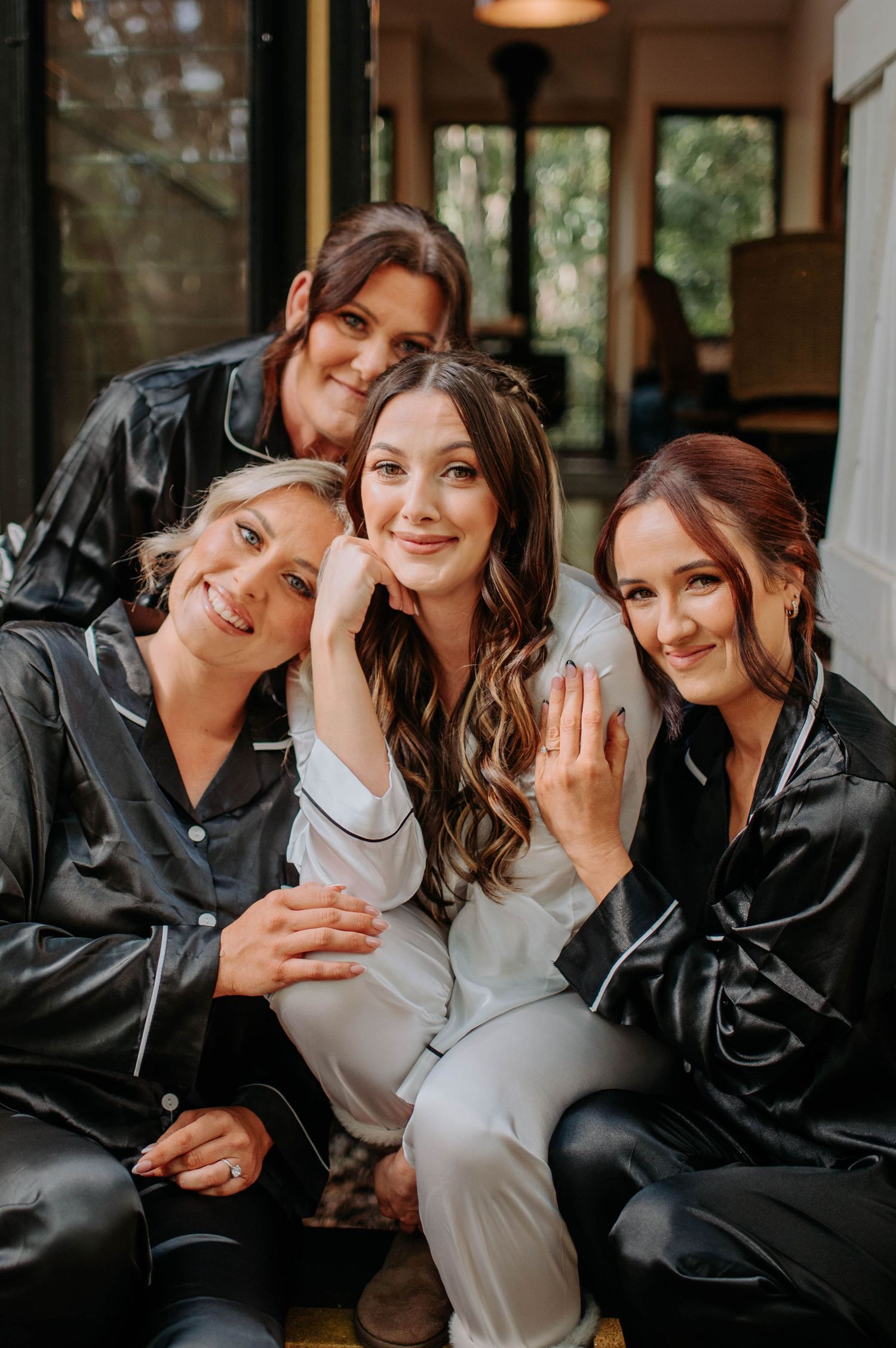 A bridal party in black silk robes poses together for a candid photo while getting ready.