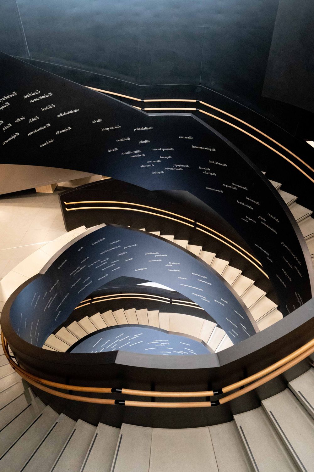 Dramatic spiral staircase with black walls and illuminated text details creating an artistic atmosphere.