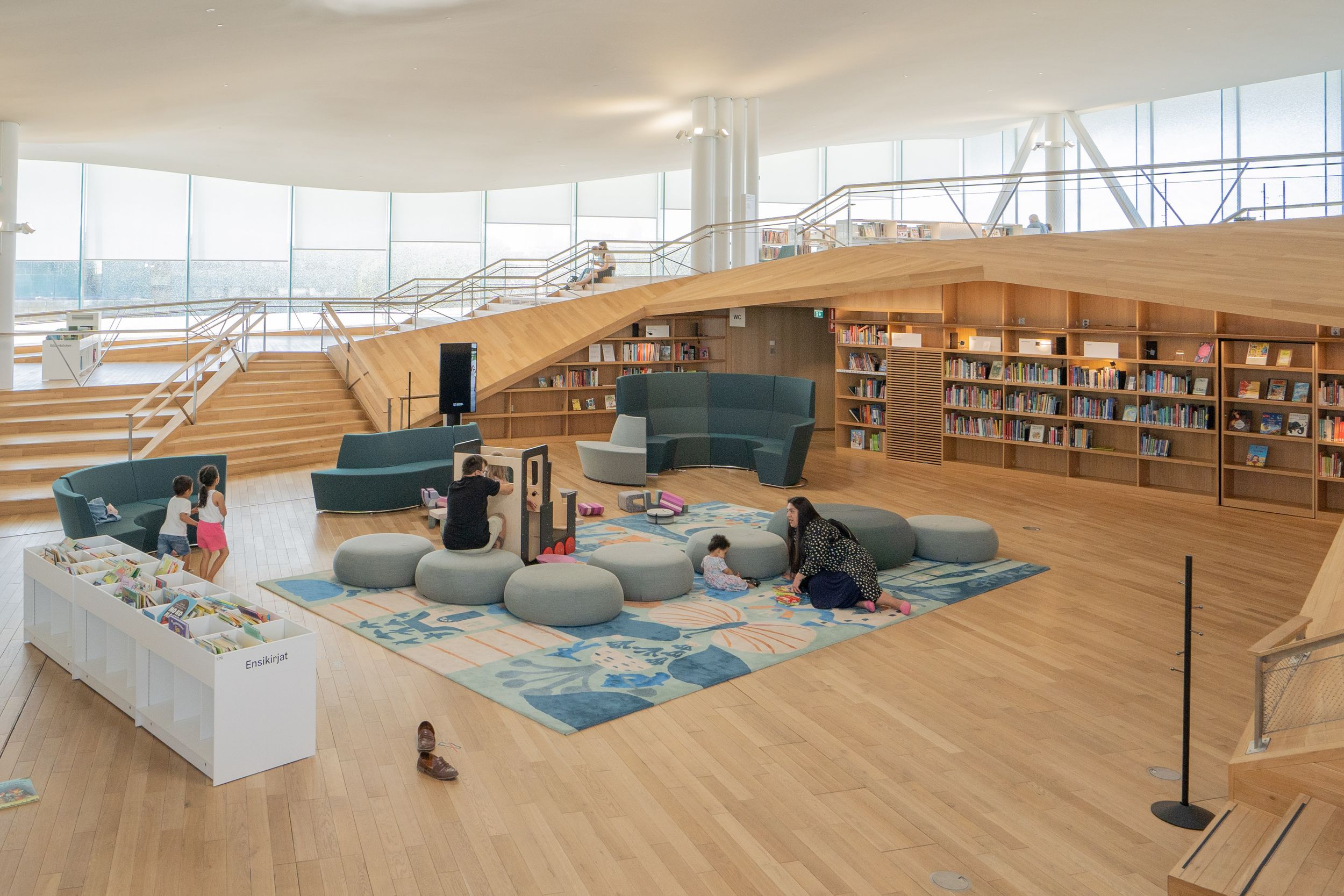 Contemporary library lounge area with comfortable seating and blue carpet surrounded by bookshelves.