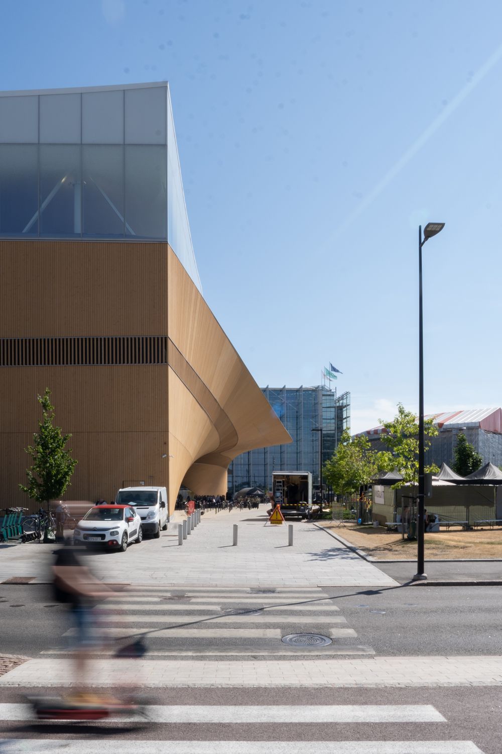 Modern building exterior with angular architecture and pedestrian crossing in urban setting.