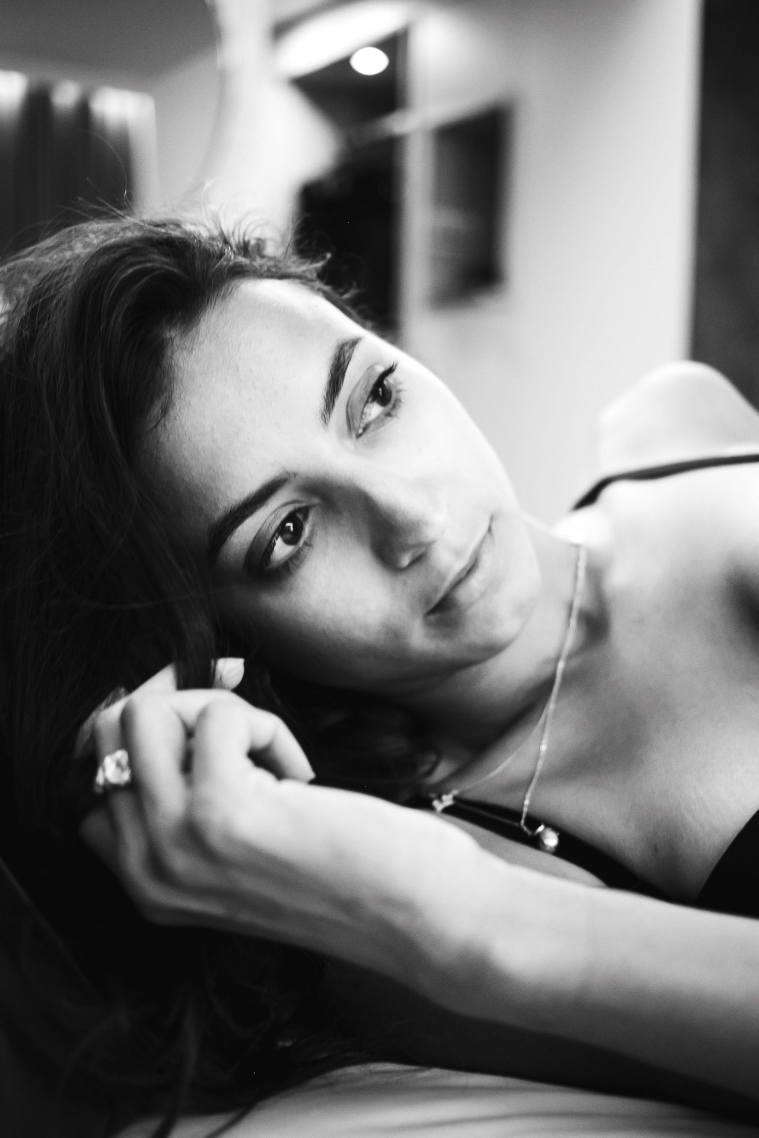Dramatic black and white close-up portrait showing contemplative expression and jewelry.