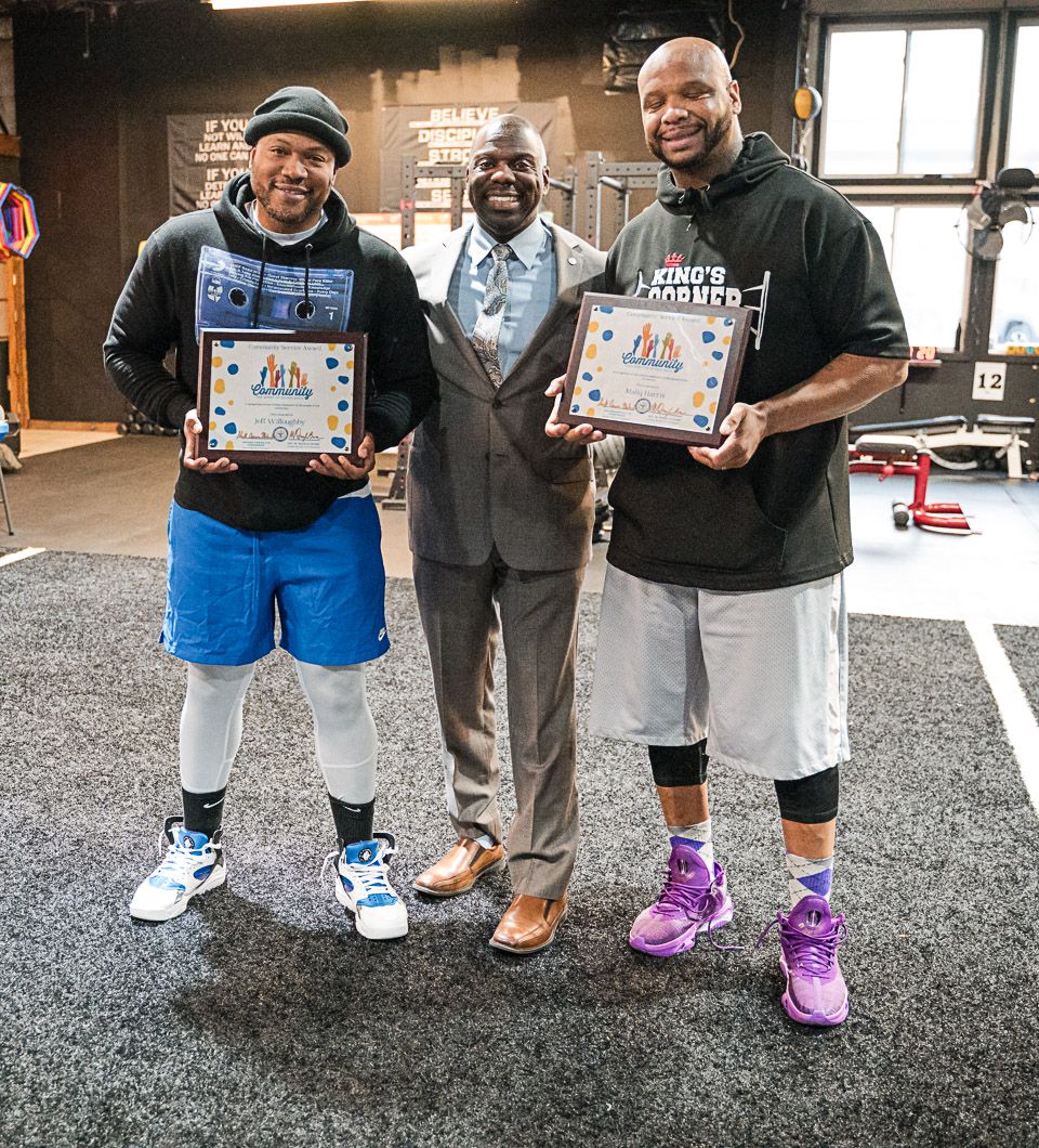 Pixs By Tina captured three people stand together in a gym space holding framed awards and smiling for a celebratory photo