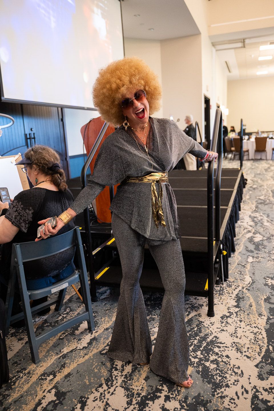 Pixs By Tina captured a woman with curly blonde hair in a dark dress dancing at a corporate family night event