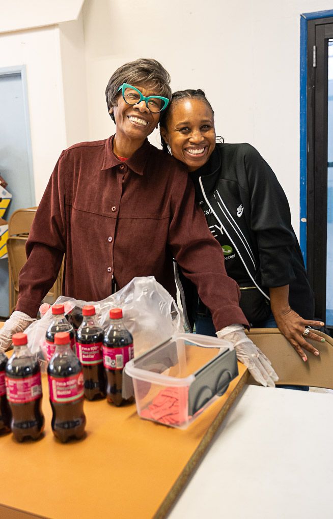 Pixs By Tina captures two ladies sharing a lighthearted moment while preparing food for pantry guests